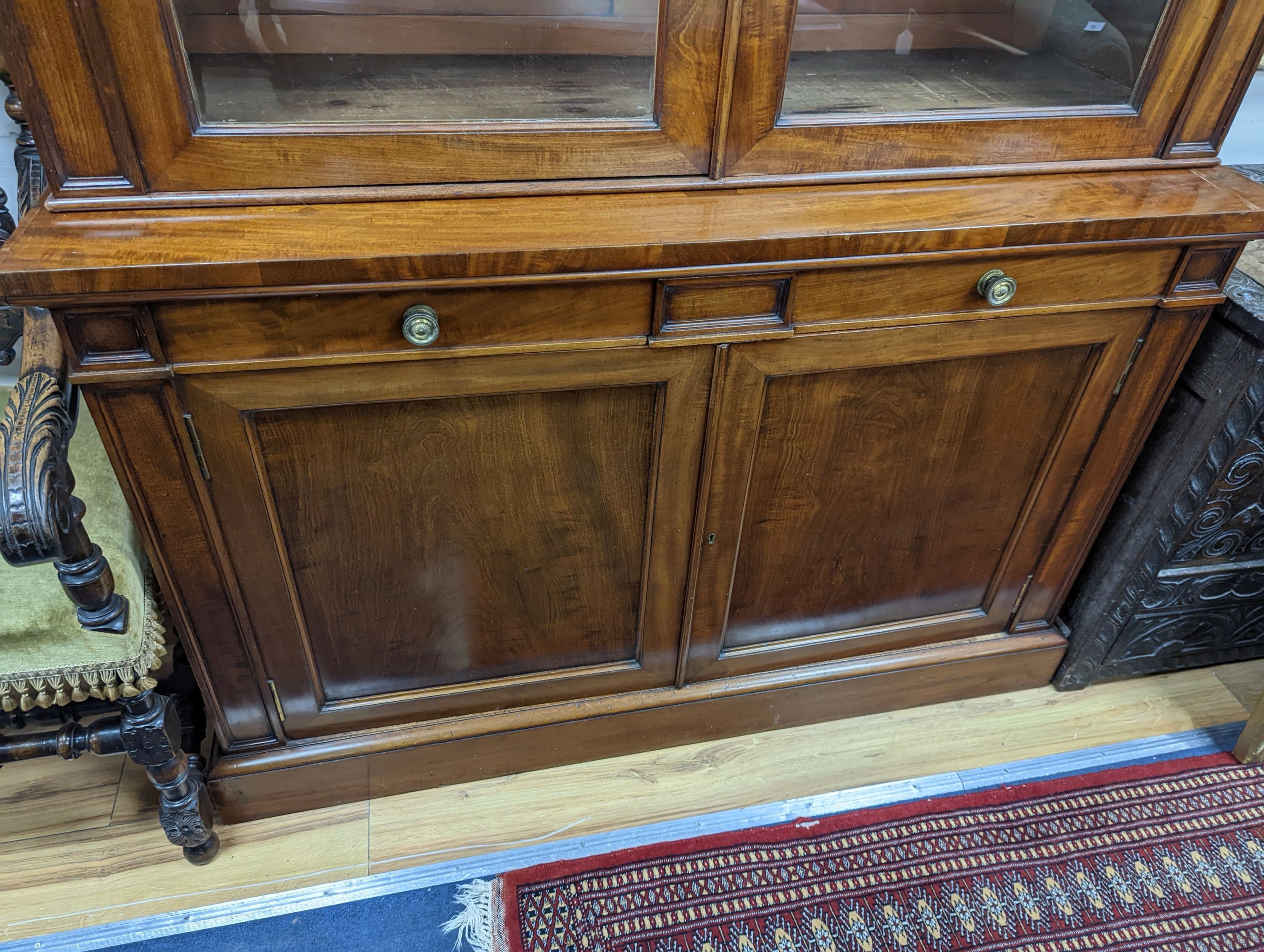 A Victorian mahogany bookcase fitted two drawers with panelled cupboard base, length 127cm, depth 49cm, height 228cm